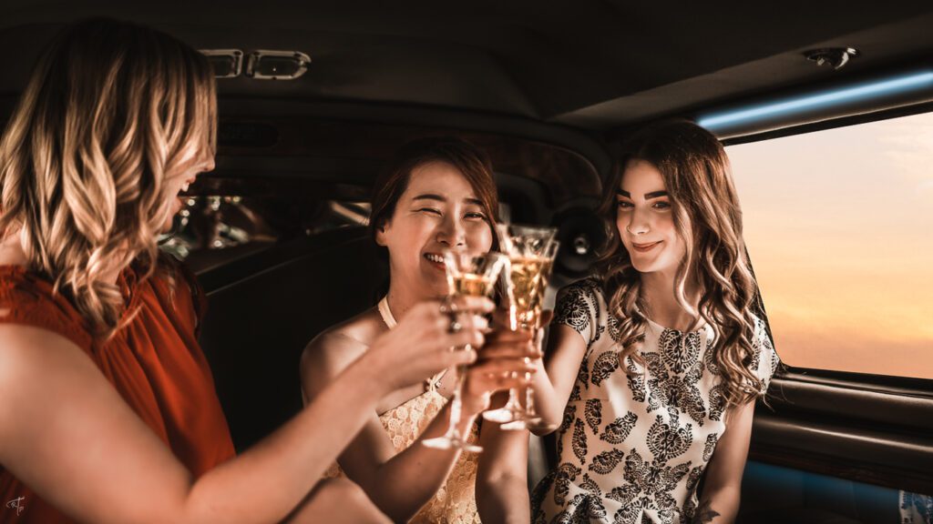 three beautiful women dressed up drinking champagne in an SUV limo on the way to dinner