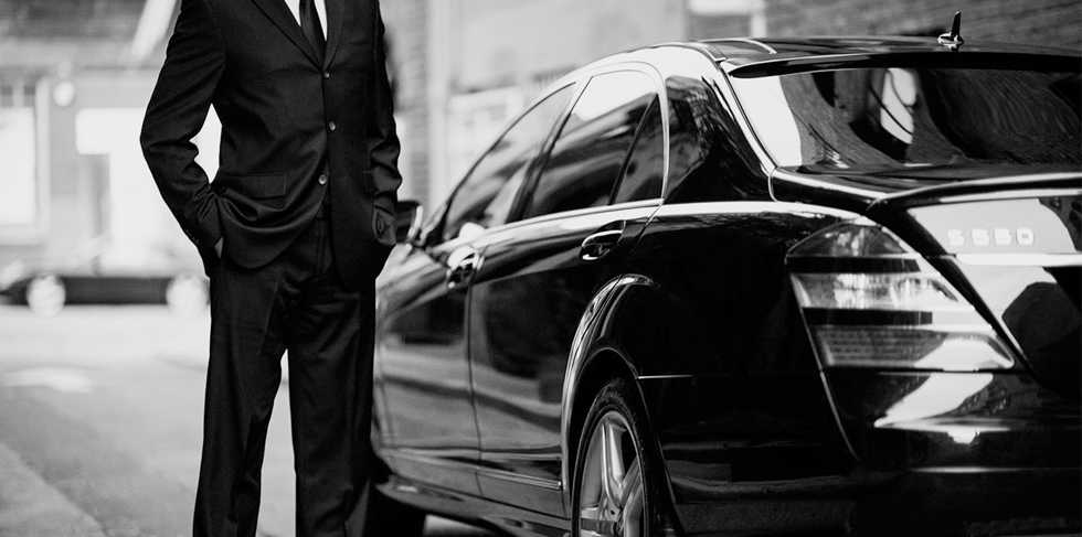 kelowna chauffeur beside black luxury vehicle